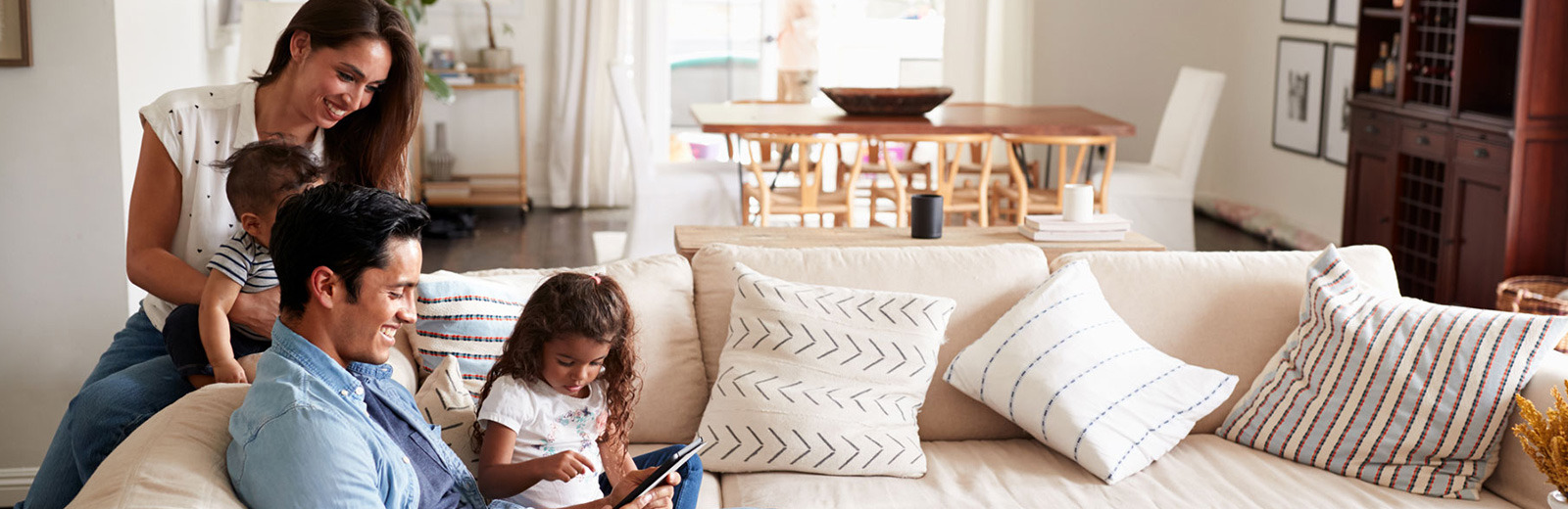 Happy family sitting on a couch looking at Property insurance.